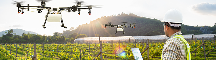An agriculture professionals using video-enabled drones as a smart surveillance solution for surveying crop yields.